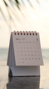 A close-up view of a hand flipping a calendar page from April to May 2027, symbolizing planning for the upcoming month and monthly strategic goal setting. Vertical, 4K resolution.