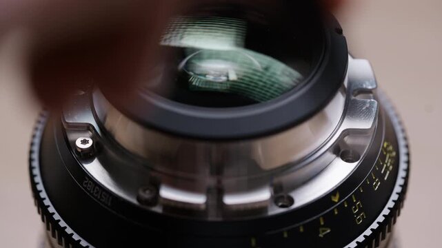 Close-up of hands tightening screws on a freshly installed PL mount on a cinema lens. Final assembly step of an EF to PL conversion. Precise and satisfying technical footage.