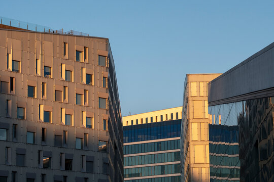 Minimal modern architecture building facade skyline cityscape with warm sunset reflections on glass planes under sky clouds background creating a cinematic urban feel