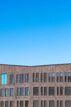 Minimal modern architecture building facade skyline cityscape framed by a curved brick edge and quiet window pattern under wide sky clouds background