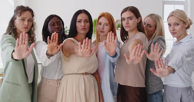 Women protest with stop hands gesture, united group. Female people face forward, serious and resolute, opposing harassment and abuse, asserting refusal and unity. Clear solidarity no and team 