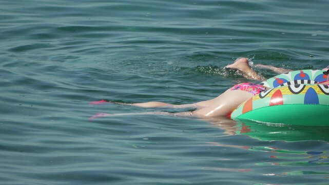 Snorkeling floating ocean, woman relaxes on inflatable ring while man explores underwater.
