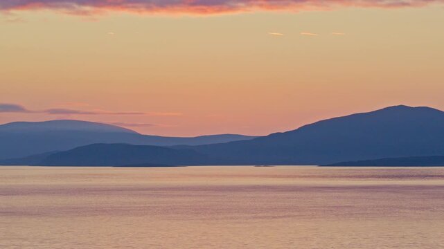 Kokelv, Hammerfest, Finnmark, Norway - The Calm Waters Reflect the Soft Hues of the Setting Sun, Casting a Serene Glow Over the Distant Mountains - Static Shot