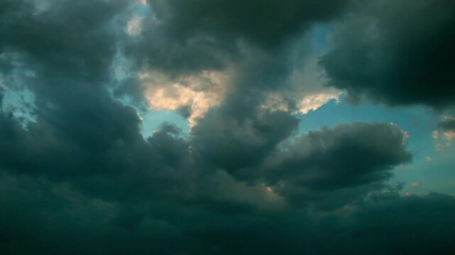 Sunlight breaking through large clouds in blue sky creating dramatic cloudscape, natural atmosphere with soft light rays and scenic weather pattern in open sky environment
