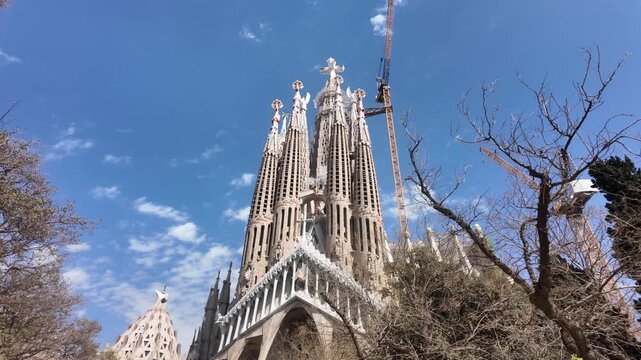 Wide view of Sagrada Familia facade with cranes showing ongoing construction in Barcelona.