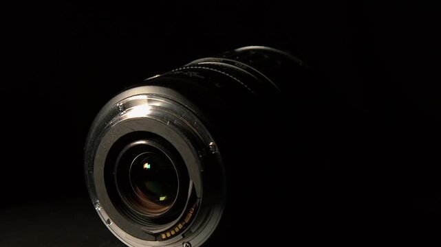 Dark moody studio: Macro zoom lens rotates in black room, side light