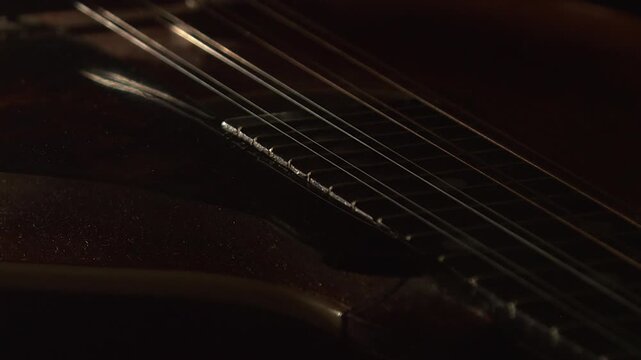 Macro closeup view of dusty old mandolin instrument rotating in dark