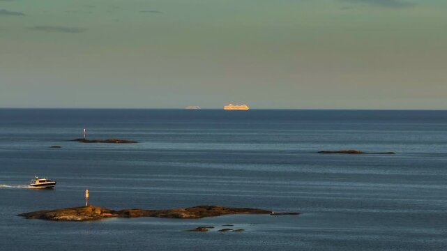 AERIAL: Peaceful maritime scene in Finland: Boat and distant ferries at golden hour