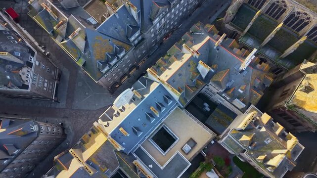 Drone view flying over historic rooftops and narrow streets of Intra-Muros old town in Saint-Malo, Brittany, France. Aerial top-down forward