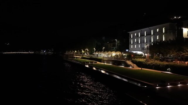 Aerial night shot of Malgrate waterfront with illuminated promenade, serene lake reflections and historic buildings.
