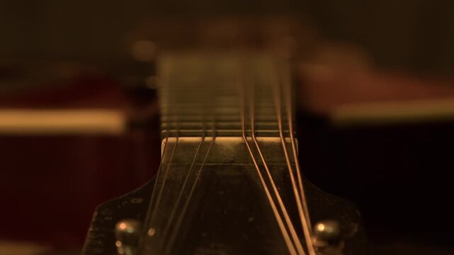 Rack focus on vintage mandolin from bridge to fretboard nut in dark