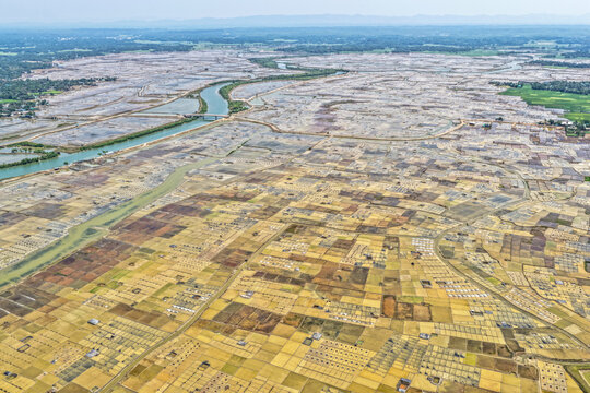 Aerial view of the landscape of salt fields with a river snaking through, contrasting with the earth tones of the fields, Cox's Bazar, Chittagong Division, Bangladesh.