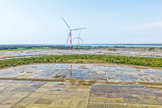 Aerial view of wind turbines casting long shadows over the patterned landscape, creating a striking contrast between modern engineering and natural beauty, Cox's Bazar, Bangladesh.