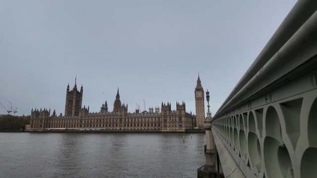 Palace of westminster and big ben with the river thames viewed from westminster bridge on an overcast day in london, united kingdom, a famous historic landmark