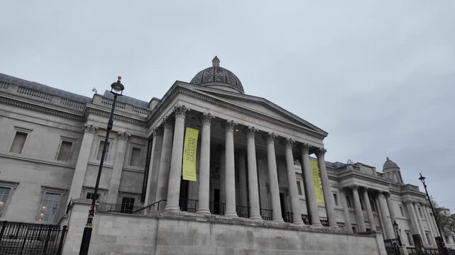 Impressive neoclassical architecture of the national gallery in london showing the iconic portico with corinthian columns and dome on a cloudy day in trafalgar square