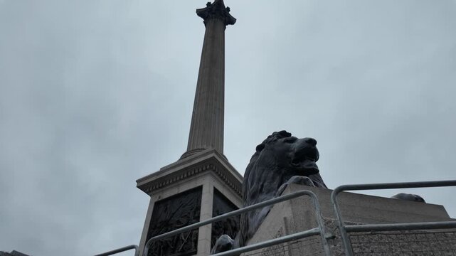 Nelson's column and a majestic lion statue in trafalgar square, london, on a gloomy, overcast day, symbolizing british history, naval victory, and national heritage