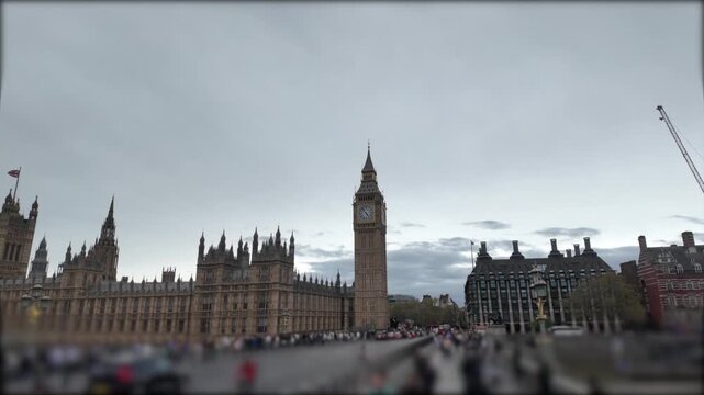 Houses of parliament and big ben tower with busy westminster bridge traffic and crowds of people walking during a cloudy day, iconic london landmark in united kingdom