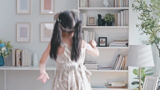 Slow motion Asian family a young daughter dancing and jumping on a soft bed in slow motion, celebrating a happy morning at home.