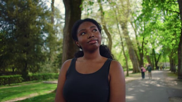 African American woman standing in park looking upward with thoughtful expression creating reflective and calm outdoor lifestyle moment in natural environment