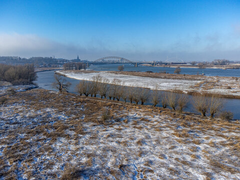 Aerial view of the snow-dusted landscape and the iconic bridge reflecting in the calm waters of the river, Tiengeboden, Gelderland, Netherlands.