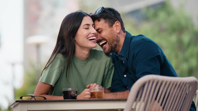 Video of tender couple talking and laughing while having a drink on a terrace in the city