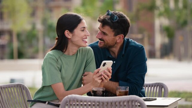 Video of tender couple talking and laughing while having a drink on a terrace in the city