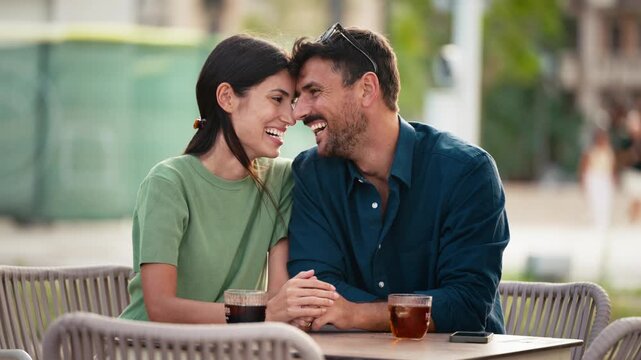 Video of tender couple talking and laughing while having a drink on a terrace in the city