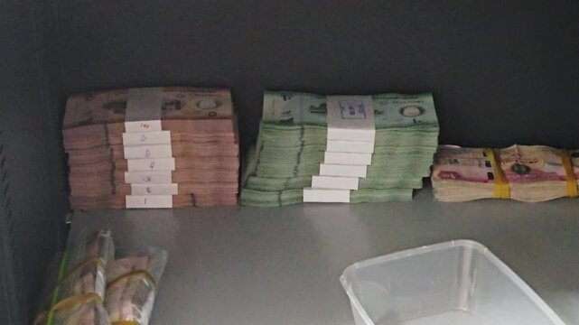 bundled stacks of uae dirham cash in various denominations arranged on a surface in a safe locker