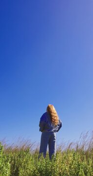 Redhead woman standing on a green grassy hill