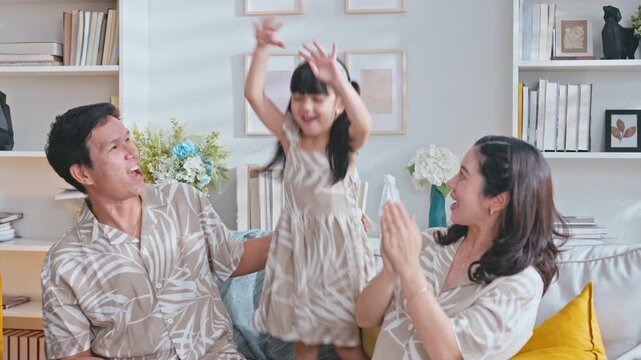 Slow motion Playful Asian family with a happy young daughter playing on sofa living room.