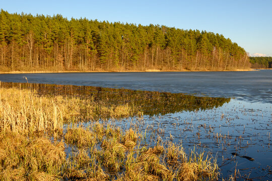 Frozen Dlugie lake at sunny spring day in Wesiory, Kashubia, Poland