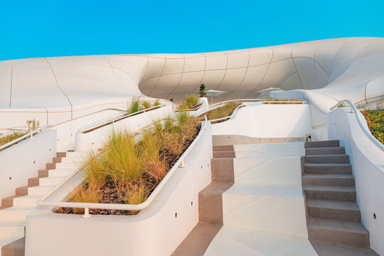 6 December 2025, Abu Dhabi, UAE: Contemporary TeamLab architecture with organic forms, winding stairs, strategically placed trees, and green plants framing a cafe entrance