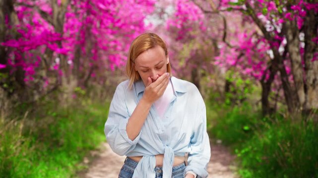 Close up of woman sneezing into tissue during spring bloom. Allergy symptoms caused by pollen, seasonal illness and health discomfort outdoors.