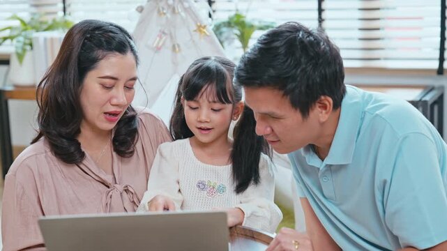 Asian family with father and mother sitting together to support their daughter's learning and homework progress at home.