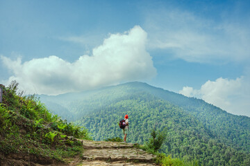 A lone hiker stands on a mountain trail with breathtaking views of the forest and clouds Madhyamaheshwar temple, Uttarakhand, india © 3 Travelers