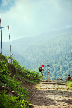 A serene mountain landscape with people on a dirt path near Madhyamaheshwar temple, Uttarakhand, India