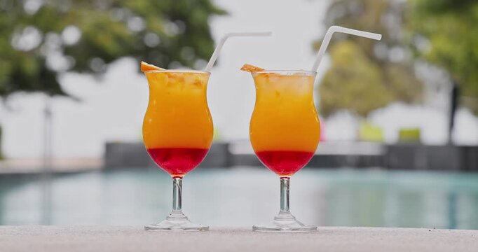 Tropical cocktails with orange slices standing, resort swimming pool, luxury travel destination, summer vacation beverage, outdoor leisure lifestyle background