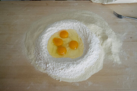 traditional process of making fresh Italian egg pasta with flour on a wooden table