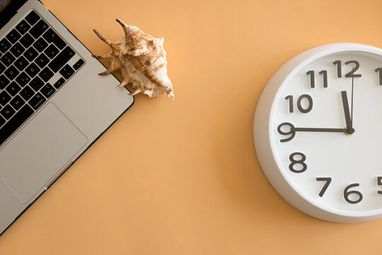 Work-life balance and travel planning concept with laptop, seashell and copy space on orange background.