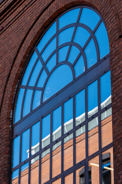 Arched window in brick facade with glass reflection showing urban architecture pattern and textured masonry with clean geometry