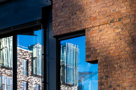 Brick and glass window reflection on a modern urban facade showing architecture contrast with textured masonry and clean lines