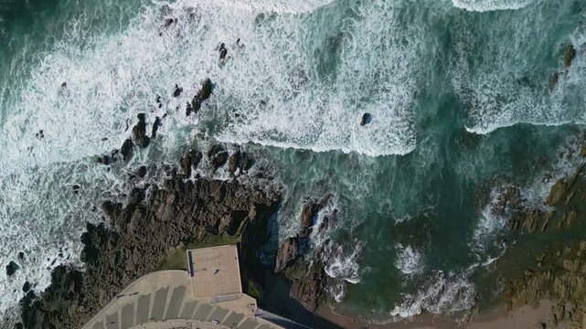 Gijon Spain aerial drone top down view of stormy ocean waves and white foam texture.
