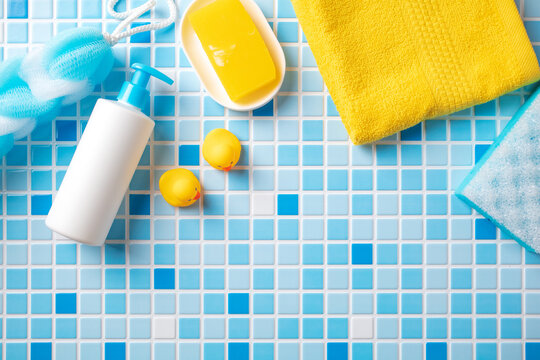 Baby body care set with soap, sponge and rubber duck toys on blue and white mosaic tiles background