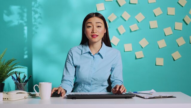 Cheerful professional businesswoman in online telemeeting videocall chating with coworker in bright colourful office. Smiling employee in video teleconference meeting sitting at desk in workplace