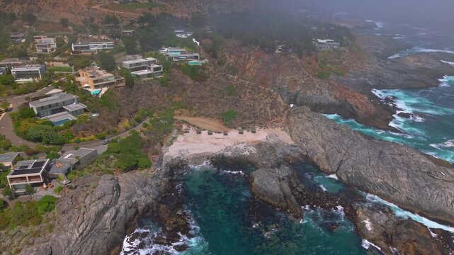 Aerial tilt up Punta Pite Beach, Valparaiso coastline reveals blue sea cliffs and waterfront resorts in Chile, travel landscape