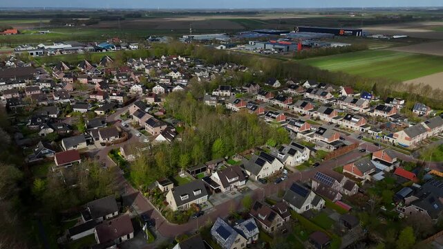 Drone footage of the Dutch village of Ens, Noordoostpolder, Flevoland, the Netherlands. Higher altitude flyover with industrial area in the background.