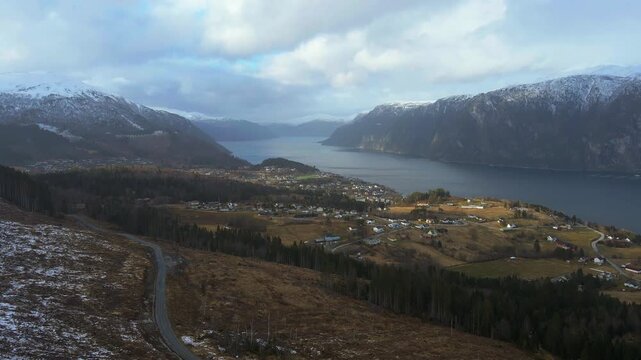 Scenic drone shot of a small town Stranda in Norway that lies beside a fjord and tall mountains on a bright day