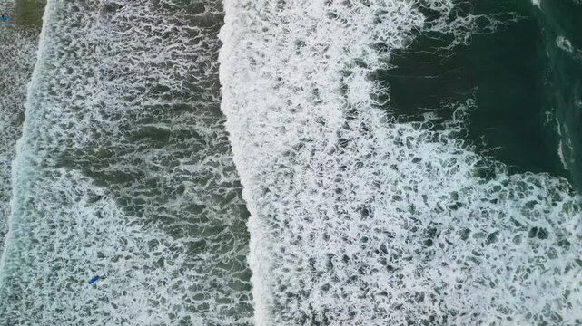 Gijon Spain aerial drone top down view of stormy ocean waves and white foam texture.
