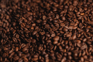 Fototapeta premium Roasted coffee beans covering tabletop surface in close view