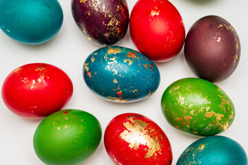 Fototapeta premium Top view of brightly colored Easter eggs with gold accents arranged on light surface, emphasizing texture, color contrast and festive decoration. Concept of minimal holiday background